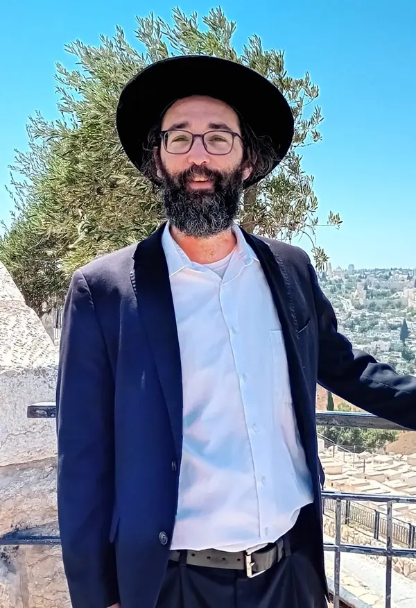 Zechariah Tokar outdoors in a black hat and suit
